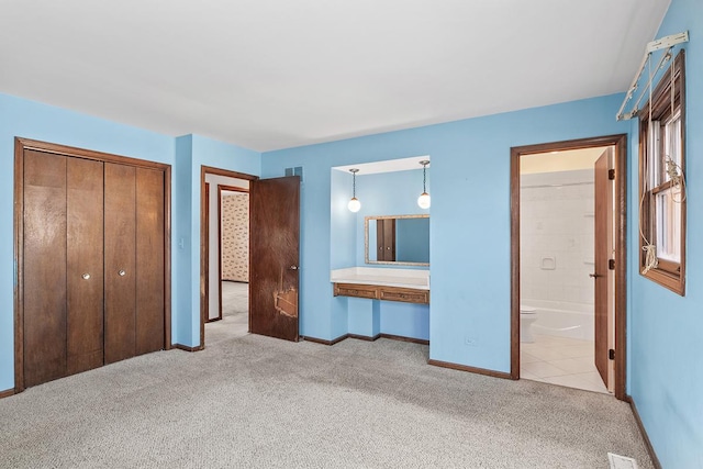 unfurnished bedroom featuring light colored carpet, connected bathroom, and a closet