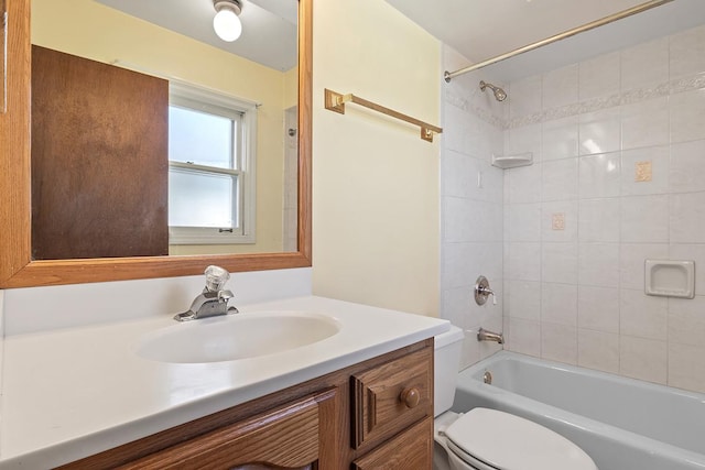 full bathroom featuring vanity, tiled shower / bath combo, and toilet