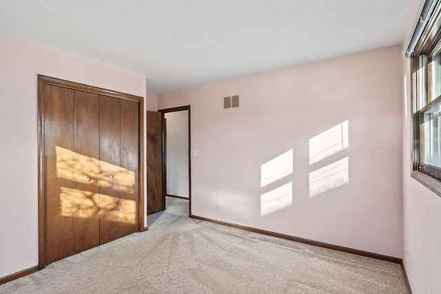 unfurnished bedroom with light carpet and a closet