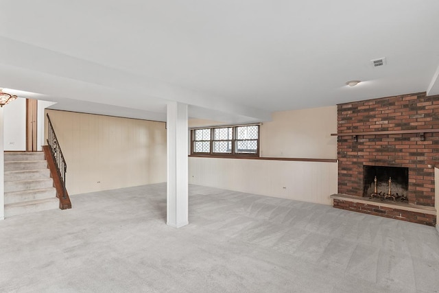 unfurnished living room featuring light colored carpet, a fireplace, and wooden walls