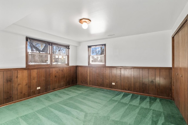 carpeted empty room with wood walls