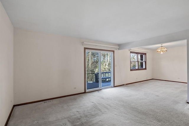 spare room with carpet floors and a chandelier