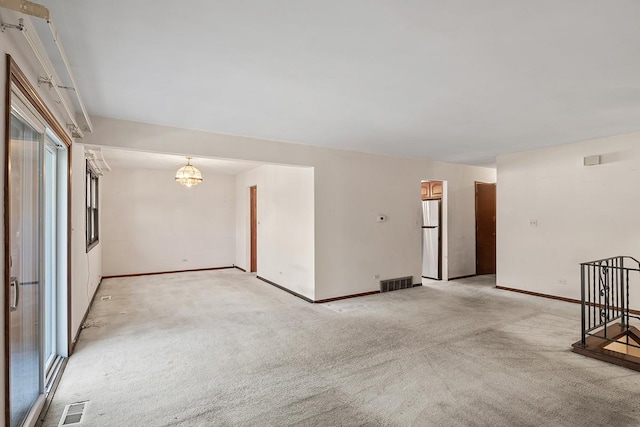 carpeted spare room featuring a notable chandelier