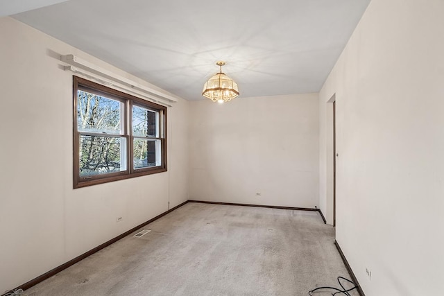 carpeted empty room with an inviting chandelier