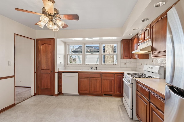 kitchen featuring backsplash, ceiling fan, sink, and white appliances