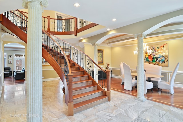 stairs featuring decorative columns, crown molding, and wood-type flooring