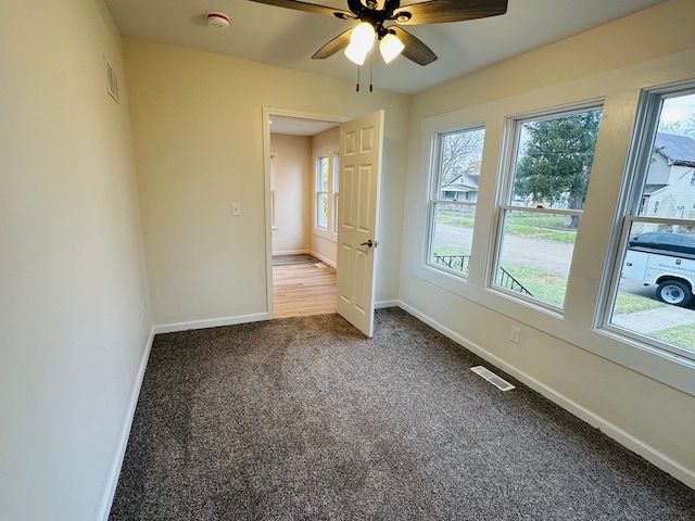 unfurnished bedroom featuring ceiling fan, multiple windows, and carpet floors