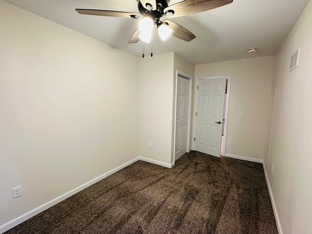 unfurnished room featuring ceiling fan and dark carpet