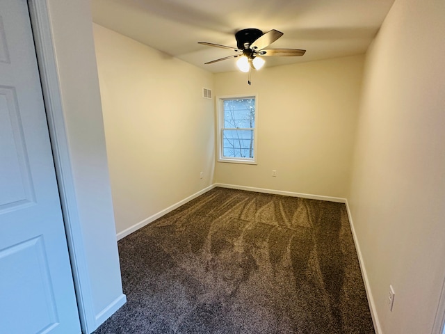 spare room featuring dark colored carpet and ceiling fan