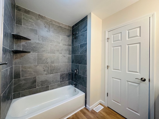 bathroom with hardwood / wood-style flooring and tiled shower / bath