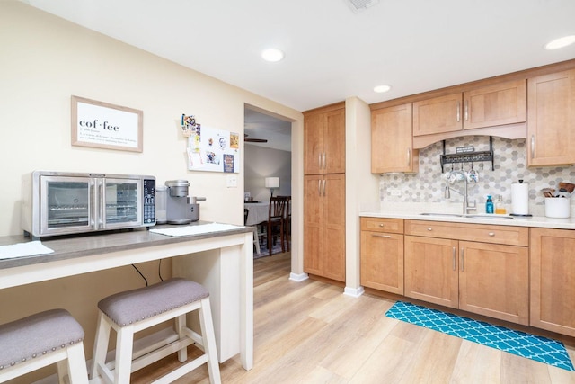 kitchen featuring light hardwood / wood-style floors, sink, decorative backsplash, and a kitchen bar