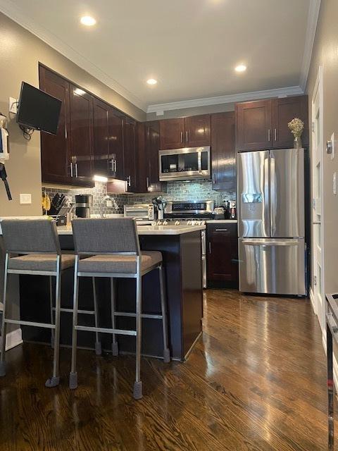 1334 S Wabash Ave Unit B, Chicago, IL 60605 - kitchen featuring stainless steel appliances, crown molding, decorative backsplash, a peninsula, and a kitchen bar