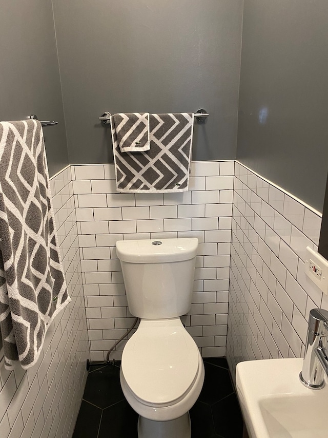 bathroom with tile walls, sink, toilet, and tile patterned flooring