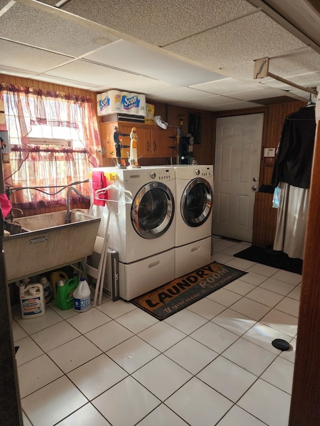 laundry room with wood walls, washing machine and dryer, sink, and light tile patterned flooring