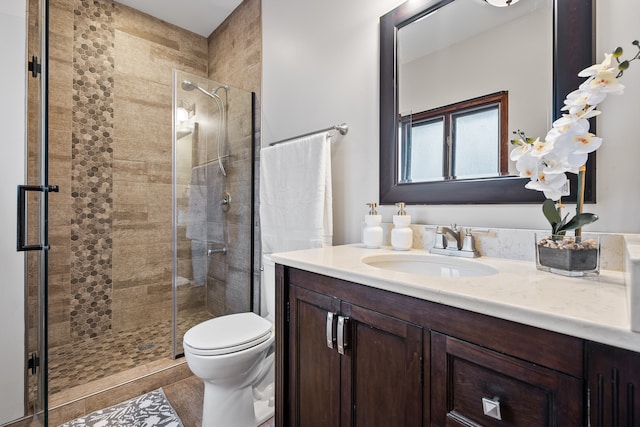 bathroom featuring tile patterned flooring, a shower with door, vanity, and toilet