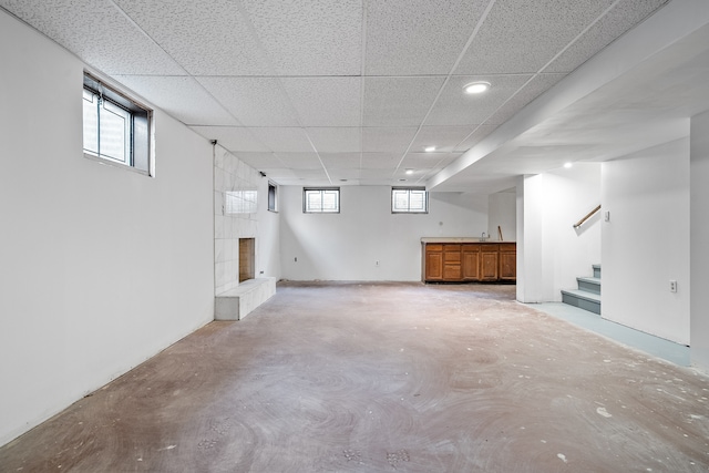 basement featuring a paneled ceiling and a fireplace