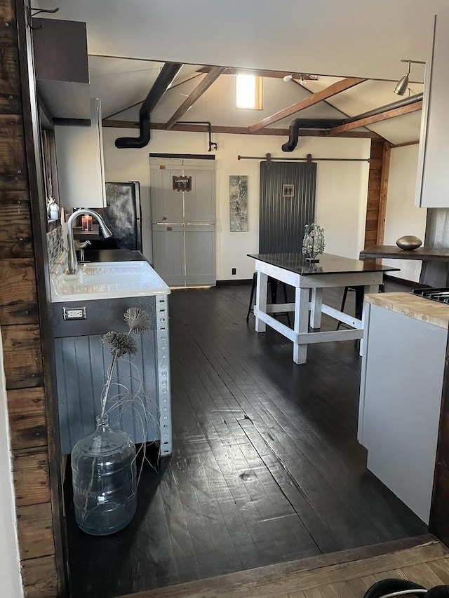 kitchen with white cabinetry, sink, beamed ceiling, and dark wood-type flooring