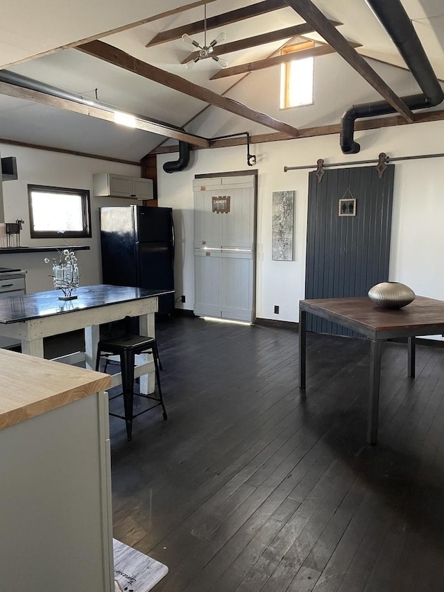 dining room featuring dark hardwood / wood-style flooring, a barn door, lofted ceiling with beams, and ceiling fan