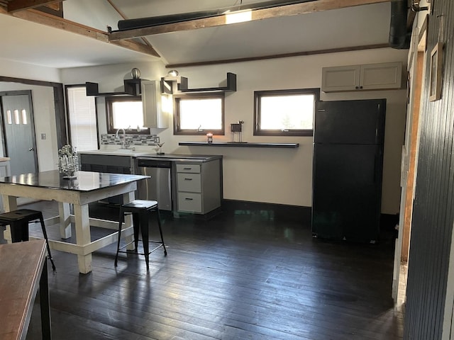 kitchen featuring tasteful backsplash, black fridge, stainless steel dishwasher, vaulted ceiling with beams, and dark hardwood / wood-style floors