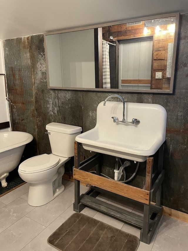 bathroom with toilet, sink, tile walls, and tile patterned flooring