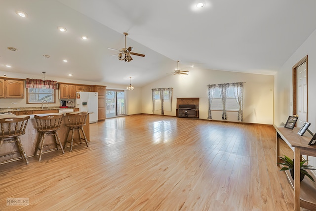 living room featuring a wealth of natural light, sink, lofted ceiling, and light wood-type flooring