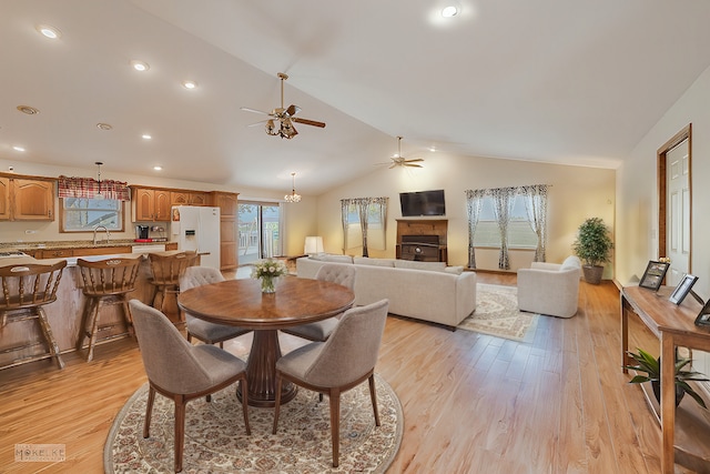 dining area with ceiling fan, light hardwood / wood-style flooring, vaulted ceiling, and sink