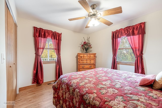 bedroom featuring ceiling fan, a closet, light wood-type flooring, and multiple windows