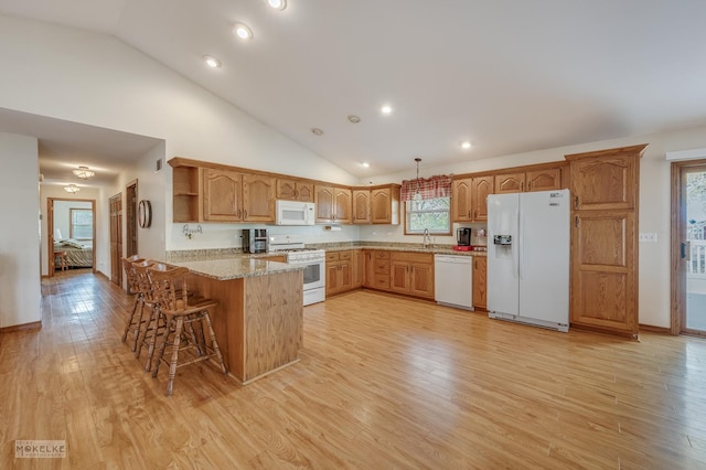 kitchen with kitchen peninsula, decorative light fixtures, white appliances, and light wood-type flooring