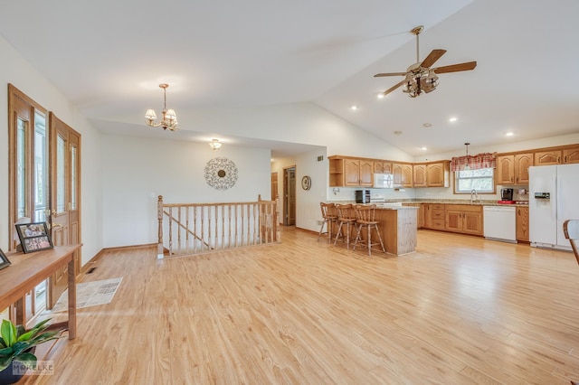 kitchen with pendant lighting, white appliances, light hardwood / wood-style floors, a breakfast bar, and a kitchen island