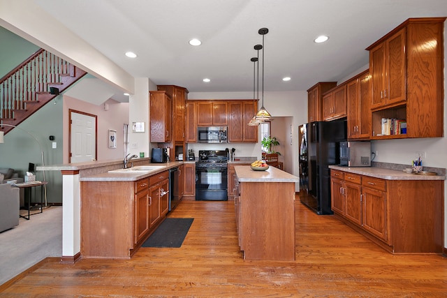 kitchen featuring light hardwood / wood-style floors, sink, black appliances, kitchen peninsula, and decorative light fixtures