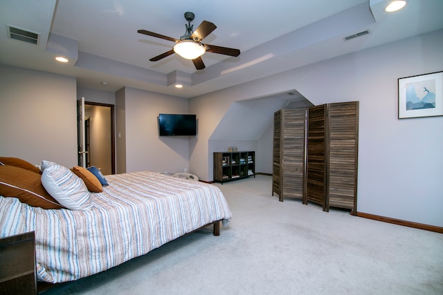 carpeted bedroom featuring ceiling fan and a tray ceiling