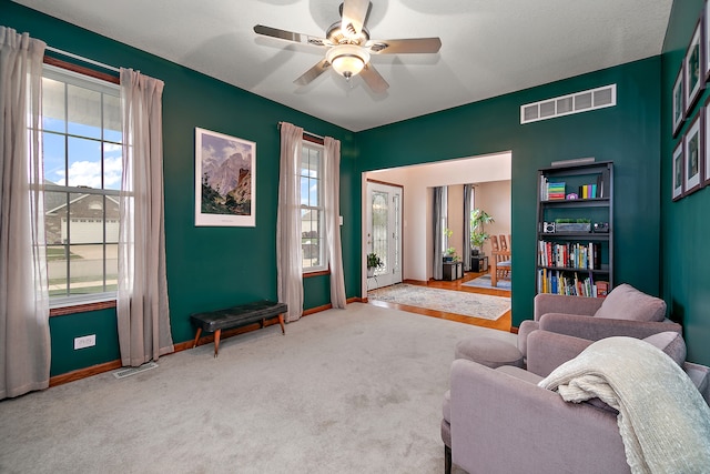 sitting room with ceiling fan and light colored carpet