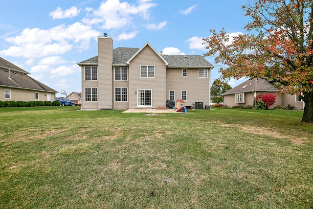 rear view of house with a lawn, central AC, and a patio area