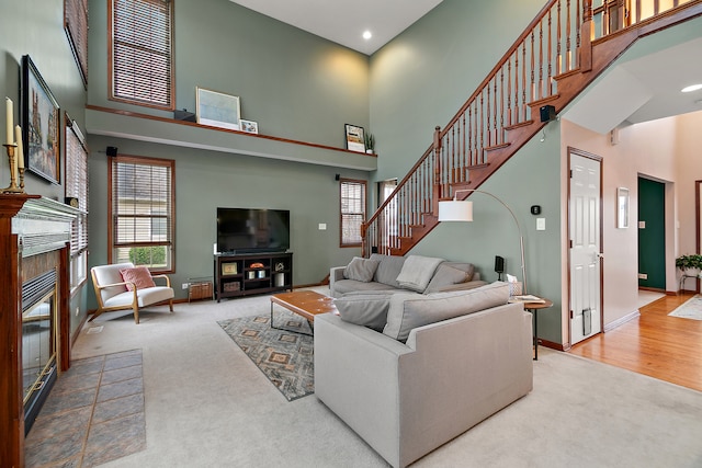 carpeted living room with a towering ceiling and a tile fireplace