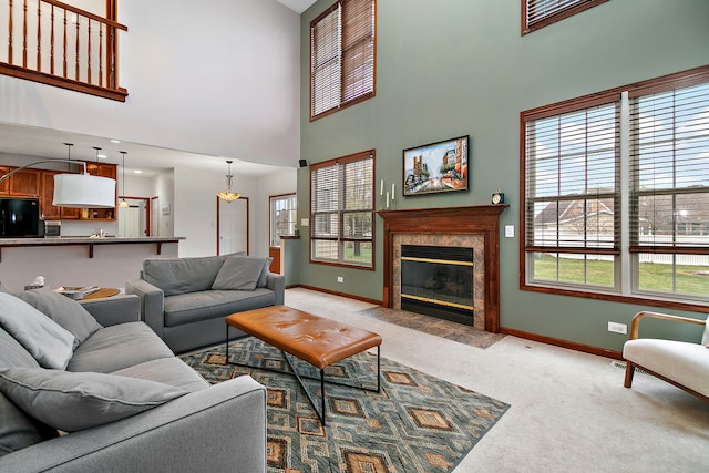 living room featuring a high ceiling, light colored carpet, a high end fireplace, and a healthy amount of sunlight