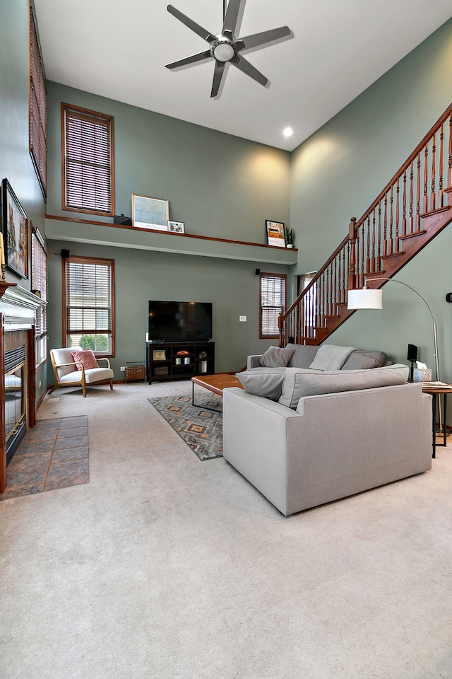 living room with carpet floors, ceiling fan, and a high ceiling