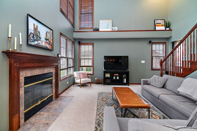 living room with a fireplace, a towering ceiling, and light carpet