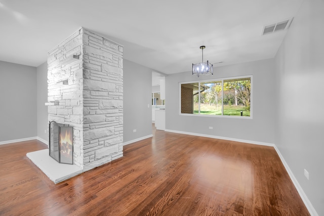 unfurnished living room featuring a chandelier, a fireplace, and hardwood / wood-style floors