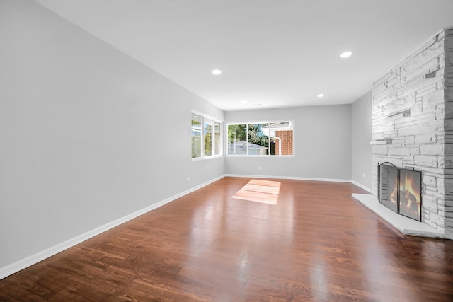 unfurnished living room with a stone fireplace and wood-type flooring