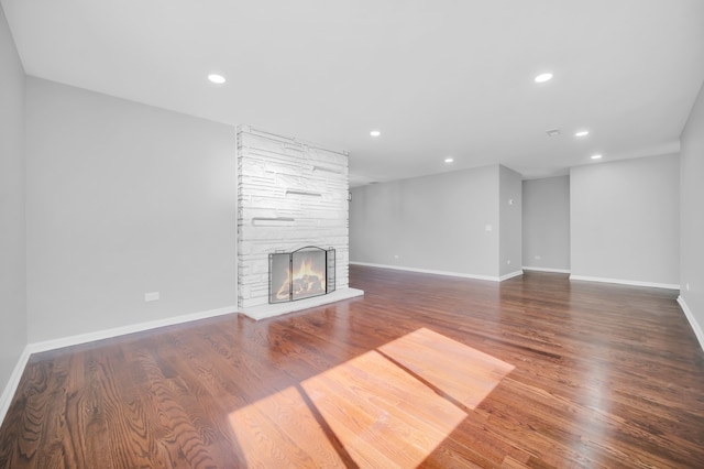 unfurnished living room featuring dark wood-type flooring and a fireplace