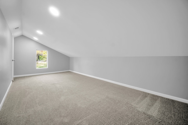 additional living space featuring carpet flooring and vaulted ceiling