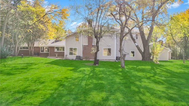 rear view of property featuring a lawn and cooling unit