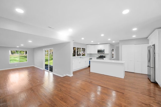 kitchen with a kitchen island, white cabinetry, stainless steel appliances, and light wood-type flooring