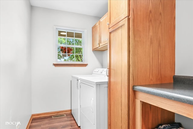 clothes washing area with cabinets, washer and clothes dryer, and dark hardwood / wood-style flooring