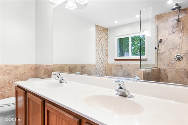 bathroom with vanity, toilet, tile walls, and tiled shower