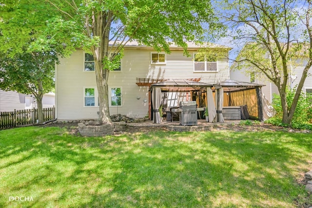 rear view of house featuring a hot tub, a gazebo, and a yard