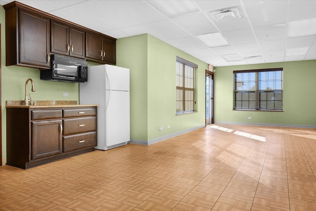 kitchen with dark brown cabinetry, a drop ceiling, white fridge, and light parquet floors