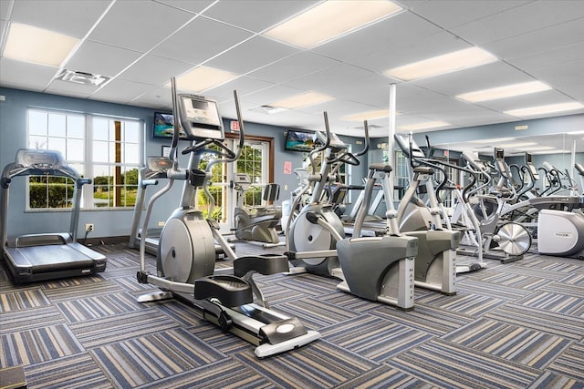 exercise room with a paneled ceiling and dark carpet