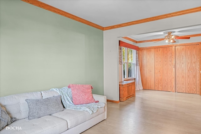 living room featuring ornamental molding, light hardwood / wood-style floors, and ceiling fan