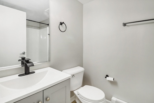 bathroom with toilet, walk in shower, vanity, and baseboard heating